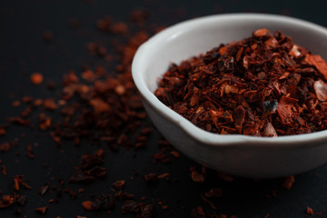 Spice red paprika in a white ceramic bowl isolated on black background