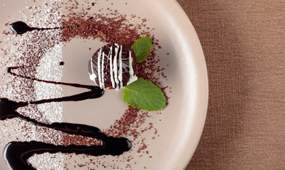 Chocolate ball with mint on a beige plate.