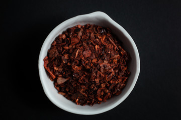 Spice red paprika in a white ceramic bowl isolated on black background