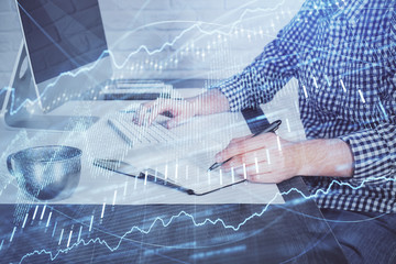 Double exposure of stock market chart with man working on computer on background. Concept of financial analysis.