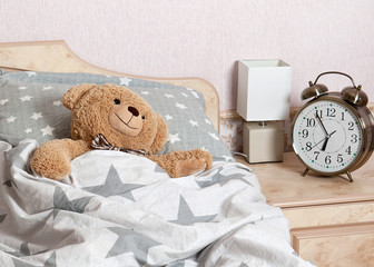 A Teddy bear sleeping in the bed in the bedroom