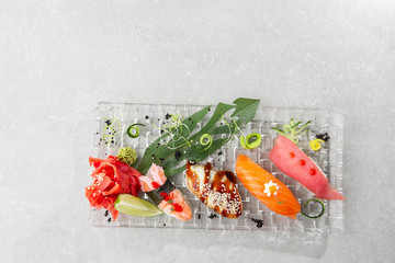 Nigiri sushi with salmon, eel, tuna and prawn, served on transparent plate. Delicious traditional Japanese food, tasty seafood, restaurant concept, food background. horizontal photo