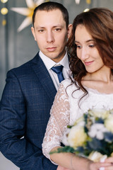 Winter wedding. Wedding couple portrait of the bride and groom. Wedding bouquet in the hands of the bride. Photoshoot on the background of a Christmas tree with a blurred background and bokeh