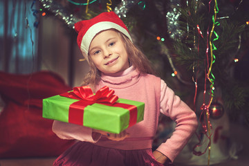 Little cute baby with a gift near the Christmas tree.