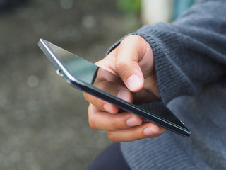  Woman in grey sweater is holding smartphone in hand..