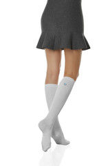 Medium back bottom shot of female figure in the gray bell-shaped skirt and white ribby knee socks...