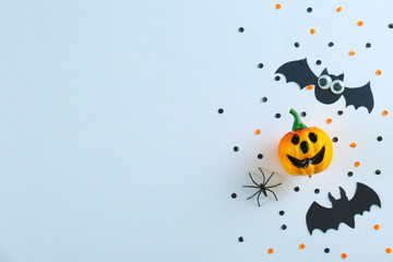 Halloween themed flat lay composition with decorative jack-o-lantern pumpkins, on paper textured background with a lot of space for text. Close up, top view.