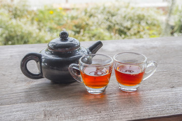 A teapot and two tea cups on a wooden floor with a rice field view