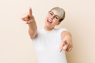Young authentic natural woman wearing a white shirt cheerful smiles pointing to front.