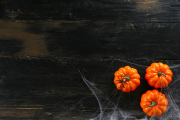 Halloween themed flat lay composition with decorative jack-o-lantern pumpkins, on dark grunged wood...