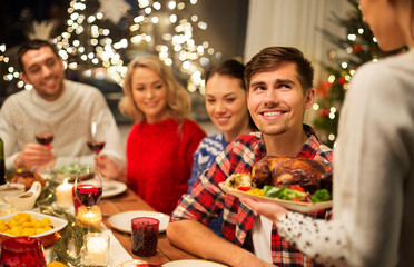 holidays and celebration concept - happy friends having christmas dinner at home