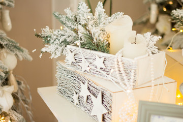 Christmas white box with candles, Christmas toys and Christmas tree branches on a shelf