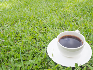 The shadow of the sky in  black coffee with white cup on the grass