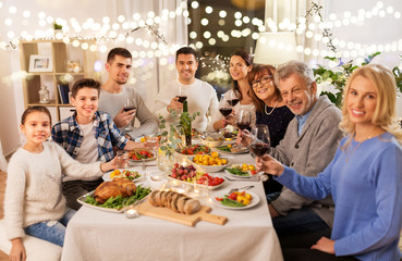 celebration, holidays and people concept - happy family having dinner party, drinking red wine and toasting at home