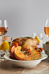selective focus of sliced baked pumpkin near grilled turkey and glasses with rose wine isolated on grey