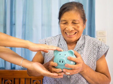 Old Woman Looking Scared Trying To Protect Her Blue Piggy Bank From Financial Fraud, Saving Money For Future Plan And Retirement Fund Concept