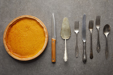 top view of tasty pumpkin pie near cutlery on grey stone surface