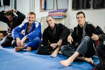 Foto op Aluminium Bjj Brazilian Jiu JItsu Athletes at the academy sitting on the tatami after training wearing kimono gi © Miljan Živković