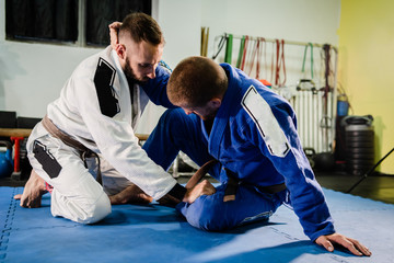 Brazilian Jiu Jitsu BJJ martial arts training sparring at the academy two fighters in butterfly...