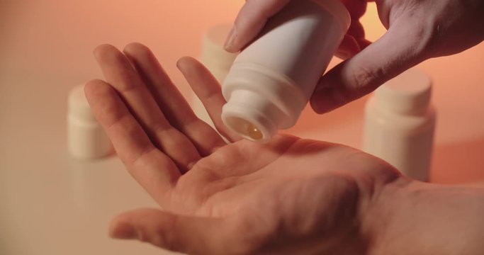 Man taking pills from a tablet can, representing modern addiction to drugs, vitamins and medicine - close up 4k footage