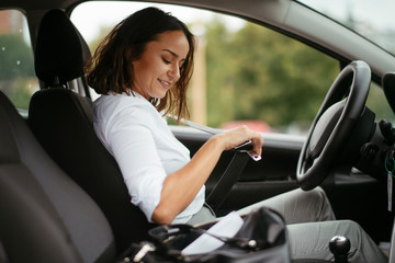 Obraz na płótnie Canvas Woman in car putting seat belt on