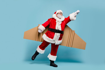 Full length body size view of his he nice fat focused purposeful St Nicholas Santa wearing warm coat plane wings flying fast hurry up delivering gifts isolated over blue pastel color background