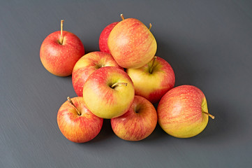 Heap of red fresh whole ripe apples full of vitamins lies on old dark scratched concrete table on kitchen. Harvest or diet concept. Close-up. Top view