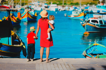 mother and kids looking at traditional boats in Malta - obrazy, fototapety, plakaty