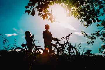 little boy and girl riding bikes in sunset nature