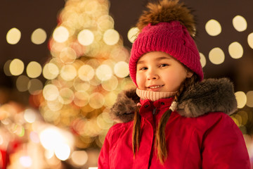 Fototapeta na wymiar holidays, childhood and people concept - happy little girl at christmas market in winter evening