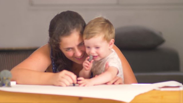 A mother playing with his little baby son of one year old, blue eyes, blonde hair, smiling and enjoying together
