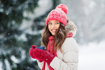 people, season and christmas concept - happy teenage girl or young woman with tea cup outdoors in winter park