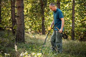 Man with electronic metal detector device, outdoor background.