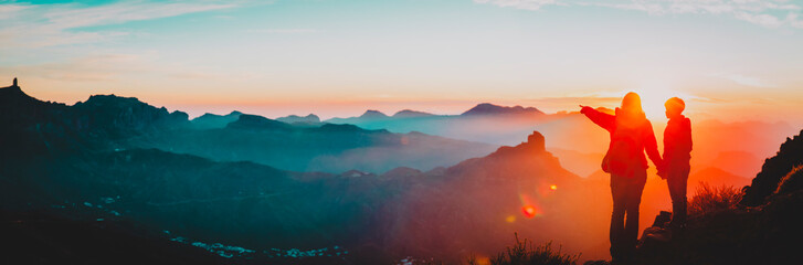 mother and son travel in mountains at sunset, panorama