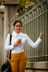 Portrait of young woman walking on the street with coffee