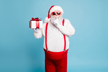 Hush its secret. Portrait of focused funny funky fat santa claus with big abdomen belly prepare gift for eve noel hold small giftbox wear red pants suspenders isolated over blue color background