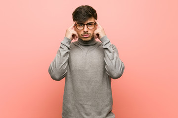 Young smart student man focused on a task, keeping forefingers pointing head.