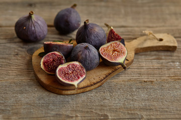 A few figs in a bowl on an old wooden background.