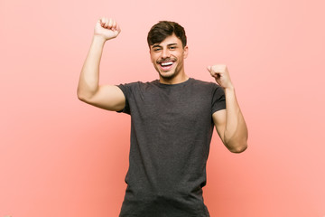 Young hispanic casual man celebrating a special day, jumps and raise arms with energy.