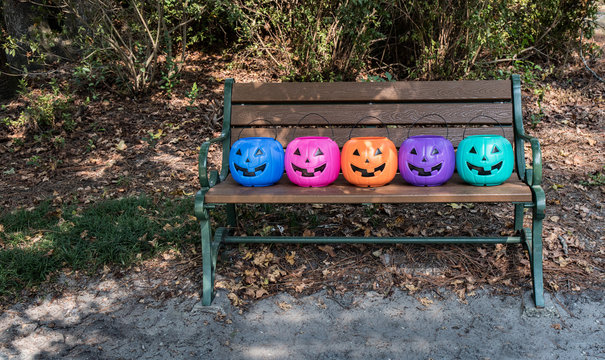 Halloween candy buckets on a bench.