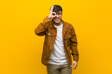 Young hispanic casual man excited keeping ok gesture on eye.