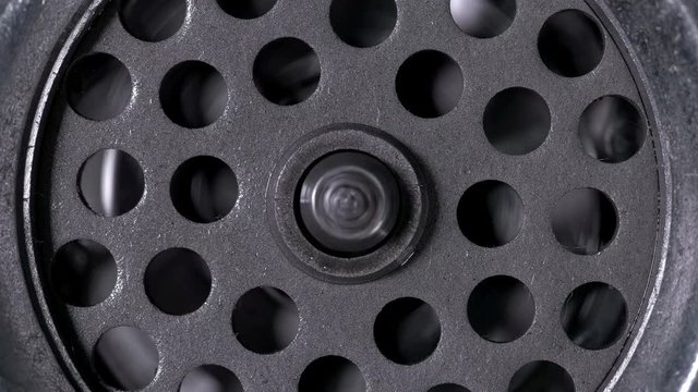A meat grinder close-up, you can see the rotation of the knife with four blades and the grill with holes through which the meat passes 4K