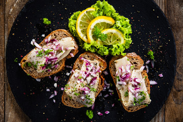Marinated herring fillets on slices of bread on black stone