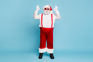 Fototapeta na wymiar Full length photo of fat funny funky christmas father with big belly abdomen show ok sign recommend winter season shopping discounts wear red overalls eyeglasses isolated over blue color background