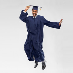 education, graduation and people concept - happy indian male graduate student in mortar board and...