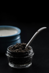 Fototapeta na wymiar Spoon in a glass jar with black sturgeon caviar.