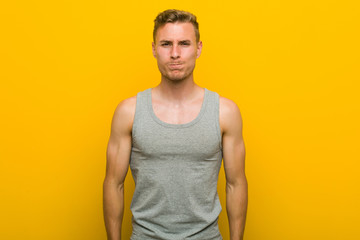 Young caucasian sport man blows cheeks, has tired expression. Facial expression concept.