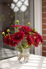  Bouquet of red dahlias in a glass vase on a white table © AnaWein