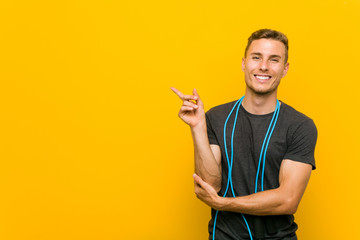 Young caucasian man holding a jump rope smiling cheerfully pointing with forefinger away.