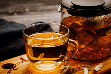 Glass cup of tea with linden on wooden table.
